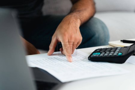 L'homme calcule l'impôt annuel au moyen d'une calculatrice et d'un formulaire de déclaration de revenus des particuliers. Saison de paiement Concept de planification fiscale et budgétaire.