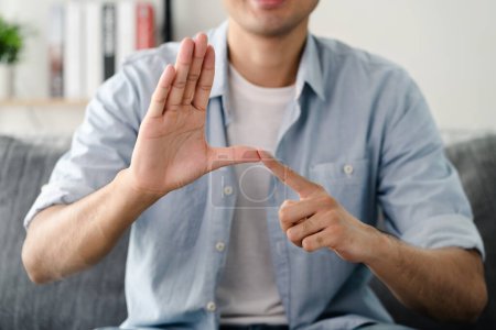 Téléchargez les photos : Heureux jeune homme sourd utilisant le langage des signes pour communiquer avec d'autres personnes - en image libre de droit