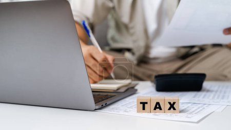 Man is calculating annual tax, monthly expenses with calculator and filling form of Individual Income Tax Return. Season to pay Tax and Budget planning concept. 