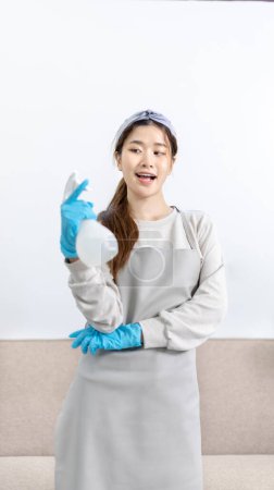 Beautiful Asian housewife wearing apron and cleaning gloves prepares to clean her house, Housework, Daily routine, Big cleaning, Clean and remove germs and dirt in the house, Clean up on weekends.