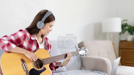 Woman artist playing the guitar and live or stream on laptop in the living room, Relaxation with music therapy, Provide enjoyment and entertainment to viewers or fan clubs, Music, Acoustic guitar.