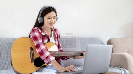 Woman artist playing the guitar and live or stream on laptop in the living room, Relaxation with music therapy, Provide enjoyment and entertainment to viewers or fan clubs, Music, Acoustic guitar.