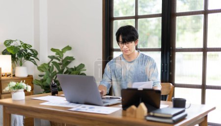 Foto de College student is analyzing data or doing homework assignments in own house, Work from home, Use your laptop to search for information and educate yourself at home, Stay home, Internet learning. - Imagen libre de derechos