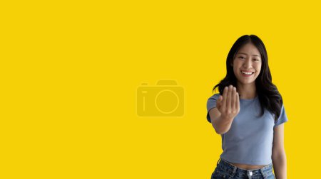 Photo for Women beckoning or inviting them to pay attention, Suggest to click or apply with me, Giving assistance and acceptance, Calling with one finger, Come and get me, Woman on yellow background. - Royalty Free Image