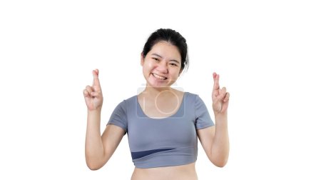 Foto de Mujer asiática joven haciendo un gesto simbólico con los dedos cruzados mostrando buena suerte, Mentira blanca gesto, Dedos cruzados, Mujer haciendo señal de mano sobre fondo blanco, Concepto supersticioso. - Imagen libre de derechos