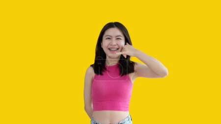 Foto de Call sign, Bright young asian woman inviting to call isolated on yellow background, Suggest to call or invite to apply for membership, Isolated on yellow background - Imagen libre de derechos