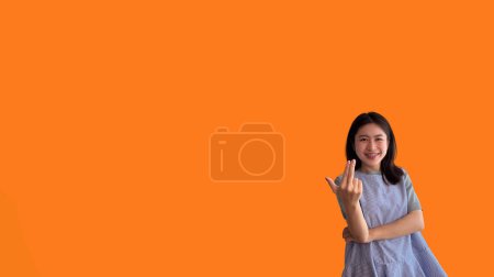 Photo for Women beckoning or inviting them to pay attention, Suggest to click or apply with me, Giving assistance and acceptance, Calling with one finger, Come and get me, Woman on orange background. - Royalty Free Image