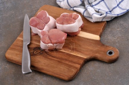 Foto de Rollos de ternera crudos en una tabla de cortar con un cuchillo y una toalla de cocina - Imagen libre de derechos