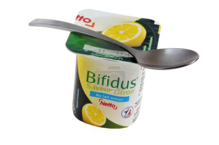 Téléchargez les photos : Yaourt au bifidus au citron de marque Netto avec une cuillère en gros plan sur fond blanc - en image libre de droit
