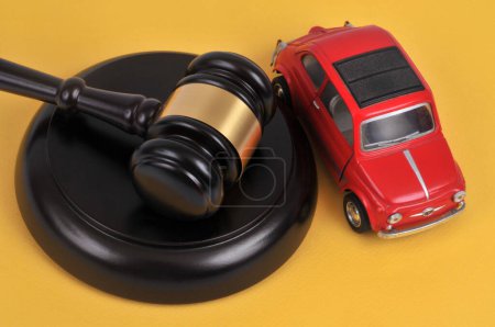 Photo for Traffic crime concept with a toy car and a judge gavel viewed from above on a yellow background - Royalty Free Image
