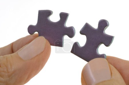 Foto de Hands assembling two puzzle pieces close up on white background - Imagen libre de derechos