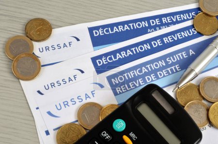 Foto de French income tax declaration and notification forms following a debt statement with URSSAF with euros and a calculator - Imagen libre de derechos
