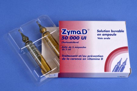 Photo for Box of ZYMAD 50 000 IU in oral solution and two ampoules in their packaging on a blue background - Royalty Free Image