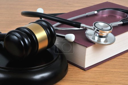 Foto de Concepto de error médico con un estetoscopio acostado en un libro y un primer plano del mazo del juez - Imagen libre de derechos