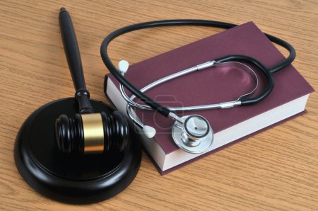 Foto de Concepto de error médico con un estetoscopio sobre un libro y un mazo de juez sobre un fondo de madera - Imagen libre de derechos