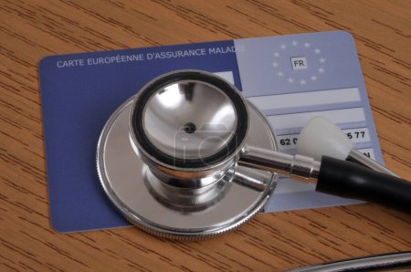 Photo for Stethoscope lying on a European health insurance card close-up on a wooden background - Royalty Free Image