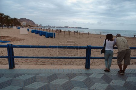 Photo for Couple looking at Alicante's Postiguet beach in the early evening - Royalty Free Image
