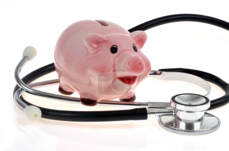 Healthcare spending concept with piggy bank and stethoscope on white background