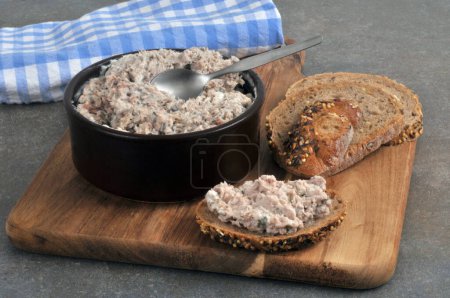 Foto de Ramekin de rillettes de atún y pan tostado sin semillas con rillettes de atún en una tabla de cortar - Imagen libre de derechos