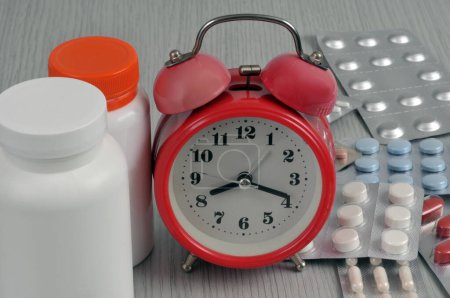 Foto de Reloj despertador con ampollas medicinales y frascos de plástico - Imagen libre de derechos