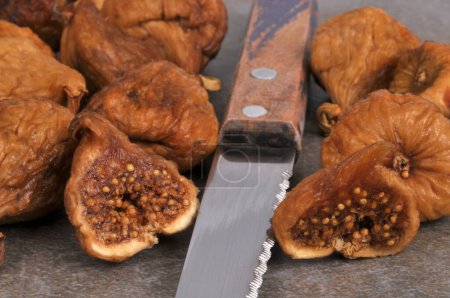 Foto de Higo seco cortado por la mitad con un cuchillo rodeado de higos secos enteros de cerca - Imagen libre de derechos
