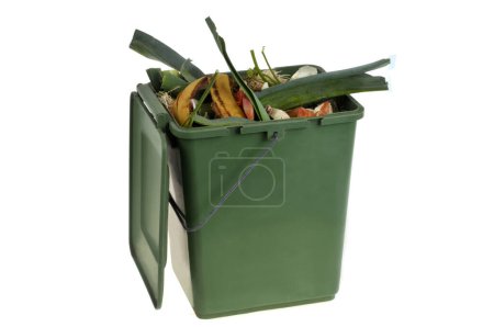 Foto de Concepto de compostaje con un recipiente de plástico verde lleno de residuos orgánicos de cerca sobre un fondo blanco - Imagen libre de derechos