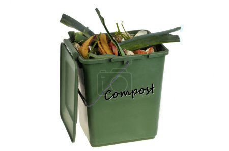 Foto de Concepto de compostaje con un recipiente de plástico verde lleno de residuos orgánicos de cerca sobre un fondo blanco - Imagen libre de derechos