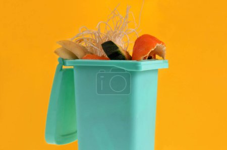 Foto de Concepto de compostaje con un bote de basura lleno de residuos orgánicos de cerca sobre fondo amarillo - Imagen libre de derechos