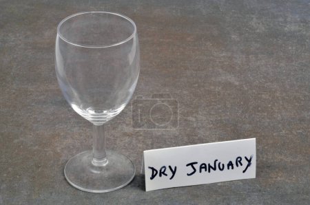 Téléchargez les photos : Concept Dry January avec un verre à vin vide et texte sur une carte sur fond gris - en image libre de droit