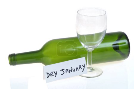 Foto de Concepto de enero seco con una copa de vino vacía y una botella sobre un fondo blanco junto a una tarjeta con texto sobre un fondo blanco - Imagen libre de derechos