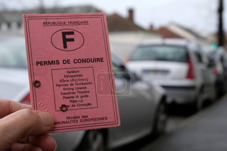 Foto de Licencia de conducir francesa en primer plano a mano con fondo de coches borrosos - Imagen libre de derechos