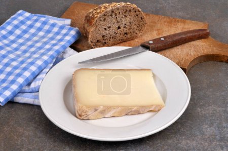 Piece of sheep tomme on a plate with a knife close-up