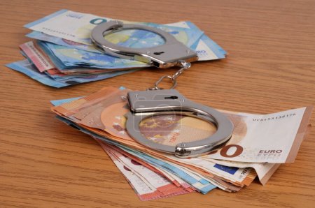 Photo for Financial crime concept with handcuffs on wads of euro banknotes closeup - Royalty Free Image