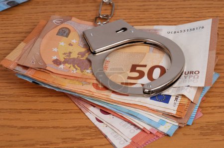 Photo for Financial crime concept with handcuffs on a wad of euro banknotes closeup - Royalty Free Image