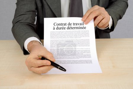 Concepto francés de contrato de trabajo de duración determinada presentado por un empresario con un bolígrafo para su firma