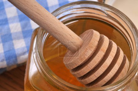 Foto de Cuchara de miel de madera en una olla de miel - Imagen libre de derechos