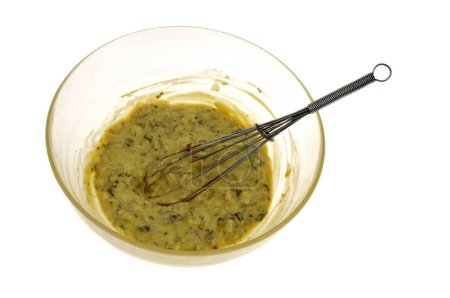 Salad bowl of homemade bearnaise sauce with a kitchen whisk close-up on a white background