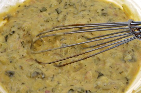 Salad bowl of homemade bearnaise sauce with a kitchen whisk close-up