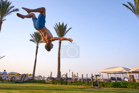Photo for Sport beach.Backflip on the beach at sunset, gymnastic on the beautiful beach with acrobatic blanche ,young man doing sport exersices with motivation context - Royalty Free Image