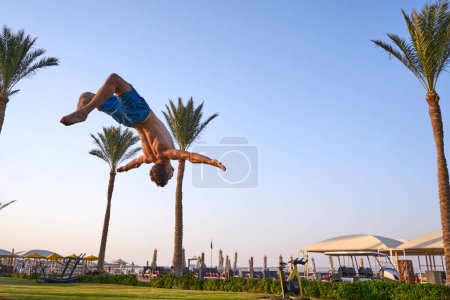 Photo for Sport beach.Backflip on the beach at sunset, gymnastic on the beautiful beach with acrobatic blanche ,young man doing sport exersices with motivation context - Royalty Free Image