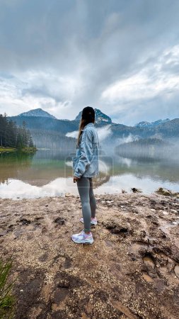 Foto de Mujer joven disfrutando de la belleza de la naturaleza mirando el lago de montaña en Montenegro - Imagen libre de derechos