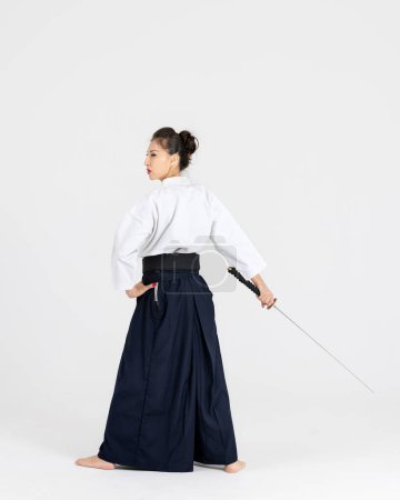 Téléchargez les photos : Maître Aïkido femme en kimono samouraï traditionnel hakama avec ceinture noire avec épée, katana sur fond blanc. Style de vie sain et concept sportif. - en image libre de droit