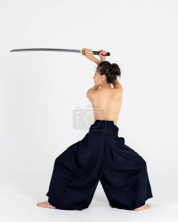 Foto de Mujer maestra Aikido en kimono hakama samurai tradicional con cinturón negro con espada, katana sobre fondo blanco. Estilo de vida saludable y concepto deportivo. - Imagen libre de derechos