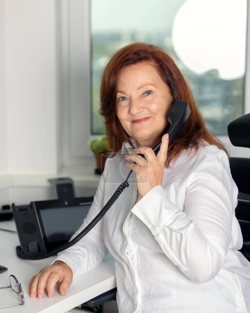 Photo for Portrait of stylish adult 60s year old woman sitting at the computer in the office, businesswoman . Confident stylish european mature middle aged woman - Royalty Free Image