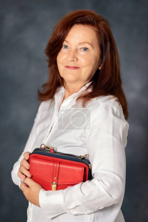 Foto de Retrato de una elegante mujer adulta de 60 años sobre fondo gris. Confiado con estilo europeo madura mujer de mediana edad - Imagen libre de derechos