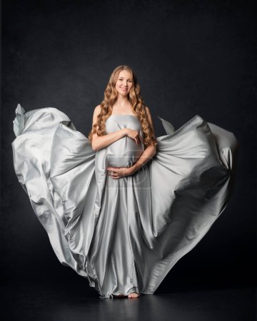 Foto de Mujer embarazada sobre fondo negro con gran barriga, esperando al bebé. Embarazo, concepto de maternidad - Imagen libre de derechos