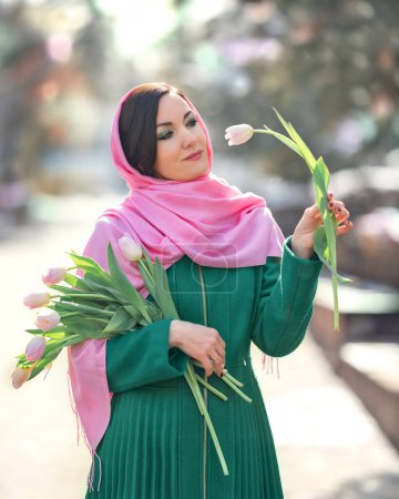 Téléchargez les photos : Belle femme avec bouquet de fleurs de tulipes printanières à la rue de la ville. Happy portrait de fille souriant et tenant des fleurs de tulipe rose à l'extérieur sur 8 Mars - en image libre de droit