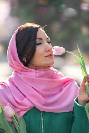 Foto de Hermosa mujer con tulipanes de primavera ramo de flores en la calle de la ciudad. Feliz retrato de niña sonriendo y sosteniendo flores de tulipán rosa al aire libre el 8 de marzo - Imagen libre de derechos