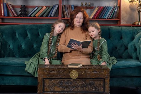 Photo for Happy grandma and grandchildren reading book together and having fun at home - Royalty Free Image