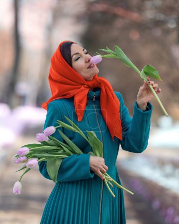 Téléchargez les photos : Belle femme avec bouquet de fleurs de tulipes printanières à la rue de la ville. Happy portrait de fille souriant et tenant des fleurs de tulipe rose à l'extérieur sur 8 Mars - en image libre de droit